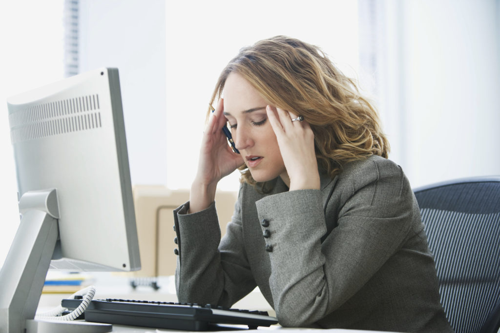 Stressed out businesswoman at desk with computer in office